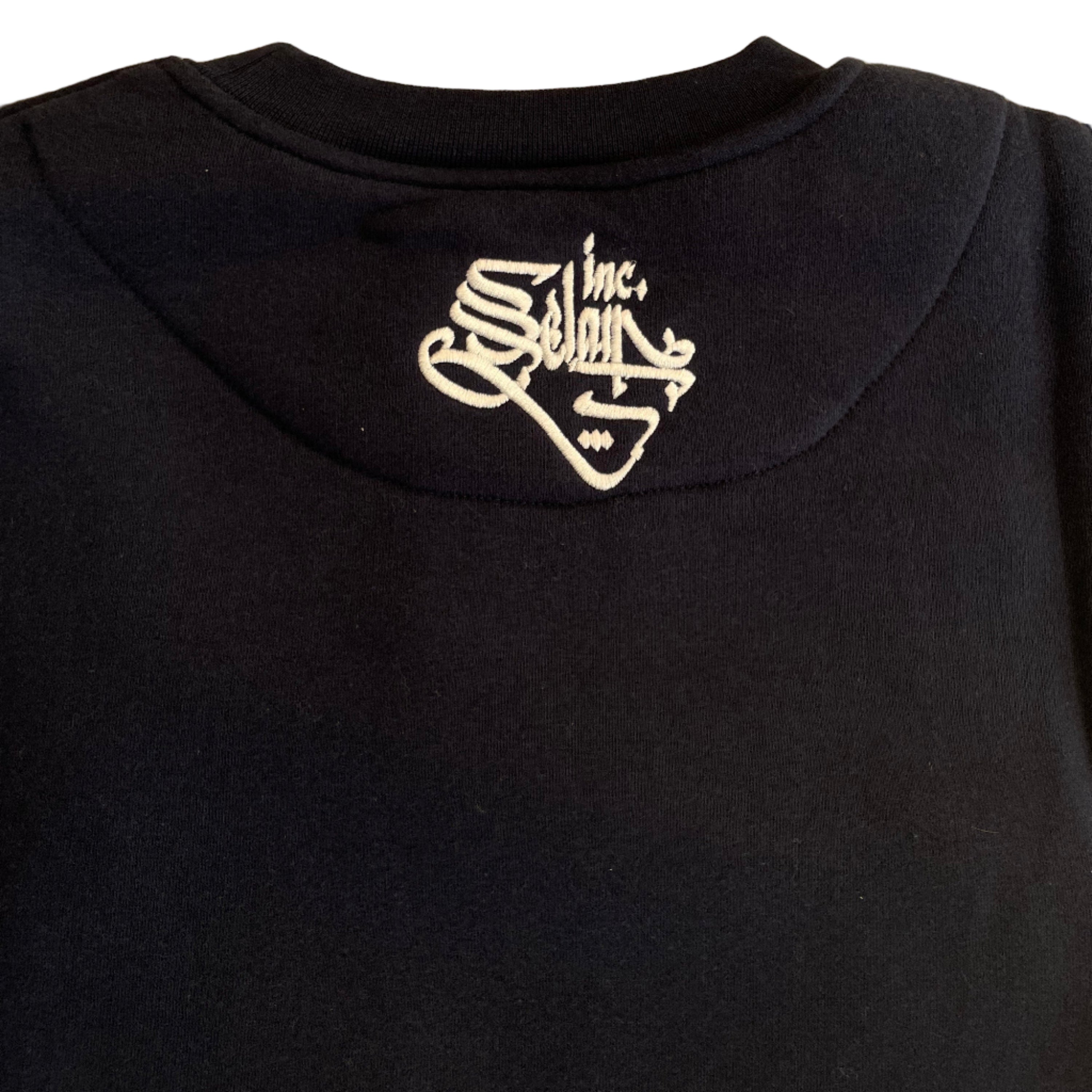 Black garment with a white logo on a textured beige background